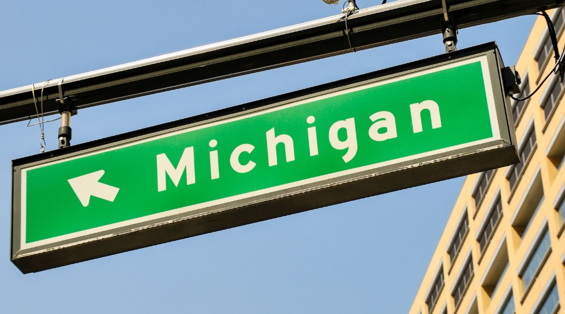a green street sign that reads Michigan with an arrow on it
